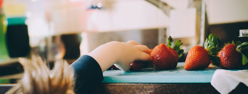 kid in the kitchen reaching for strawberries